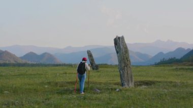 Türk dönemi antik taş stelts Altay Dağları'nda kadın turist inceliyor