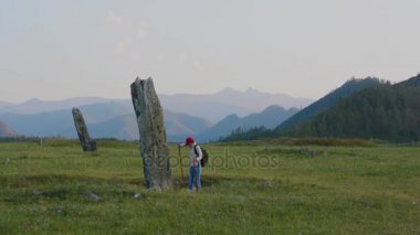 Türk dönemi antik taş stelts Altay Dağları'nda kadın turist inceliyor