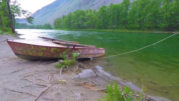 山の麓に大河川の海岸にボート — ストック動画