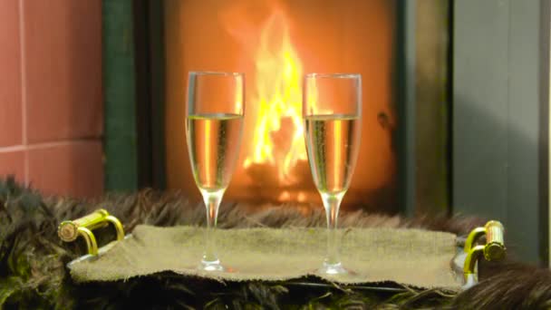 暖炉のそばで二つのグラスとシャンパンがトレイの上に立つ — ストック動画