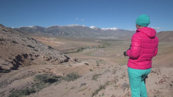 Een vrouwelijke reiziger, zittend op een rots, maakt foto 's van prachtige bergen op de camera — Stockvideo