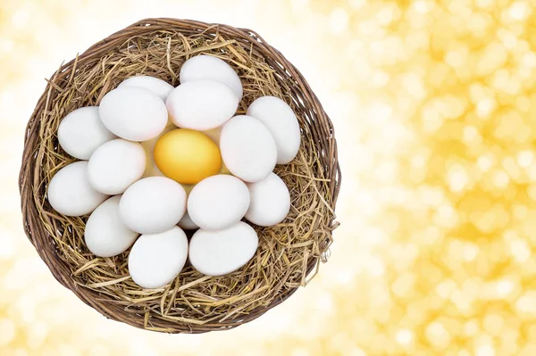Golden egg among on white eggs in wicker basket