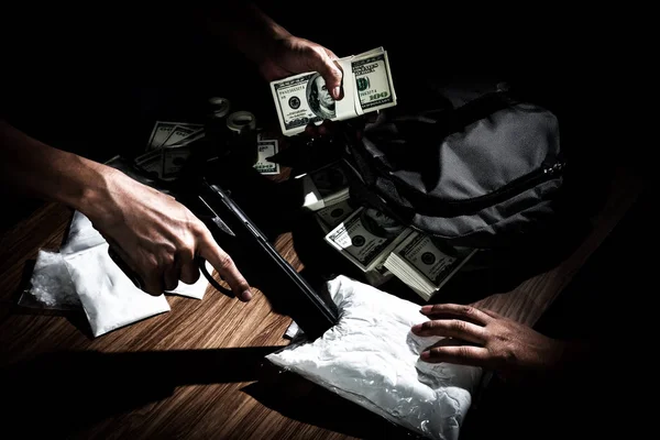 El traficante de drogas usa un arma para empujar el sobre sobre sobre la mesa al comprador — Foto de Stock
