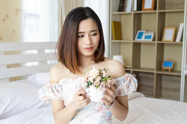 Jovem segurando um vaso com flores em casa — Fotografia de Stock