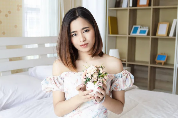 Jovem segurando um vaso com flores em casa — Fotografia de Stock