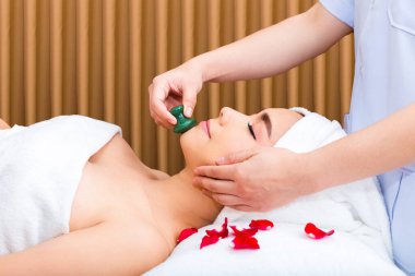 Genç ve güzel bir kadın, cilt bakımı için yüz bakımı yapan kadın terapist tarafından yapılan yaşlanmayı önleyici yüz masajının keyfini çıkarıyor. vücut ve yüz tedavisi kavramı.