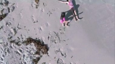 İki kız okyanus, gündüz plajda atış kum bırakmasını serin hava atış.