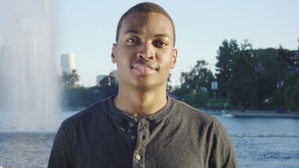 Νεαρός Αφροαμερικάνος κοιτάζει κάμερα και χαμογελά — Αρχείο Βίντεο