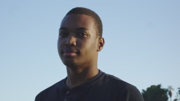 Junger afrikanisch-amerikanischer Mann schaut in die Kamera, wie sie sich um ihn herum bewegt — Stockvideo