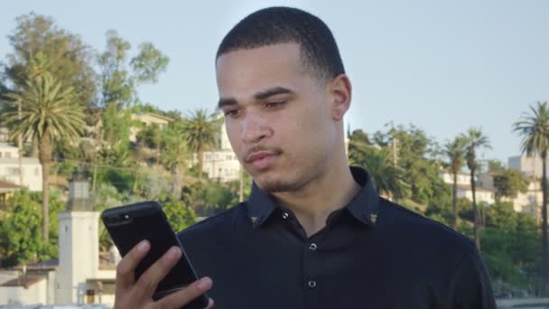 Genç adam parktaki cep telefonuna bakıyor. — Stok video