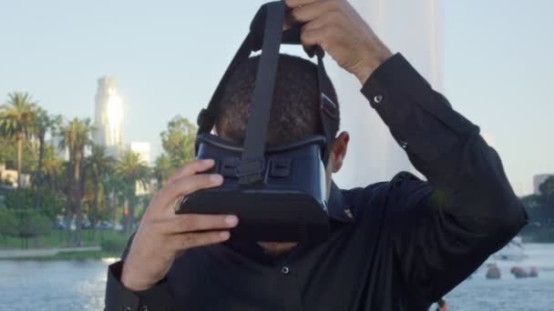 Genç Afro-Amerikalı bir adam parktaki çeşmenin yanında VR gözlükleri kullanıyor. — Stok video