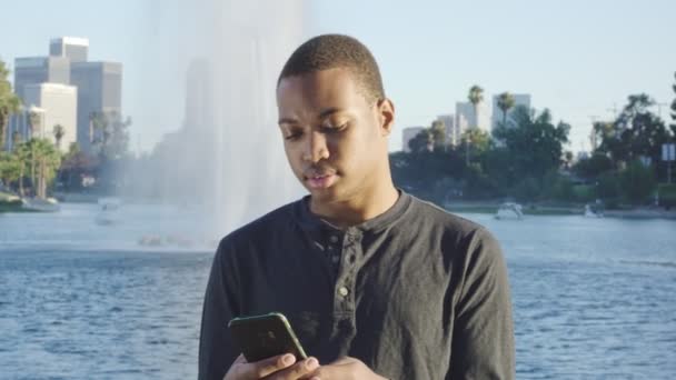 Ung afroamerikansk man använder mobiltelefon i Los Angeles — Stockvideo