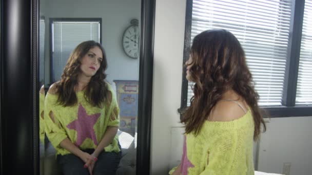 Женщина с грустным выражением лица смотрит на себя в зеркало — стоковое видео