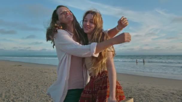 Мать и дочь на пляже обнимаются и улыбаются в камеру — стоковое видео