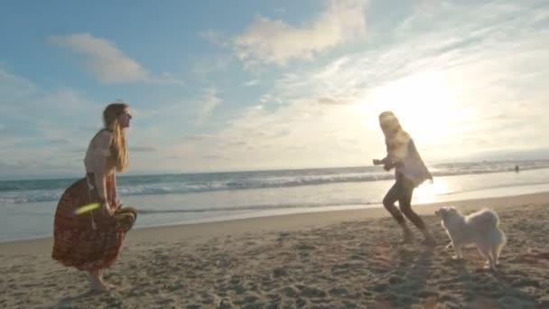 Powolny ruch matki i córki bawiących się z psem na plaży — Wideo stockowe