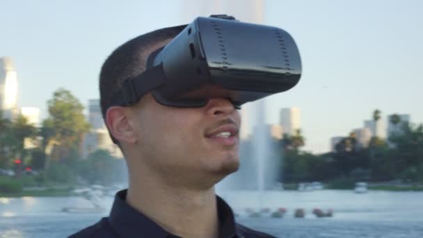 Молодой человек в очках от виртуальной реальности в парке — стоковое видео