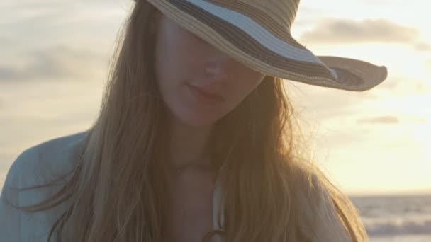 O femeie frumoasă care își folosește telefonul mobil lângă ocean în timpul apusului de soare — Videoclip de stoc