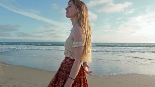 Joyeux jeune femme aux cheveux longs marchant sur la plage — Video
