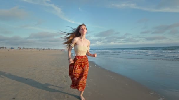 Медленное движение молодой женщины, бегущей вдоль океана к камере — стоковое видео