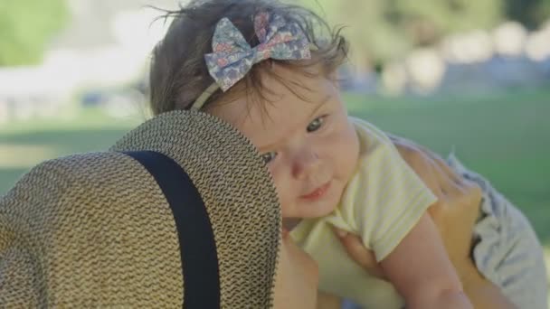 Närbild av vacker bebis som hennes mamma håller henne högt i parken — Stockvideo