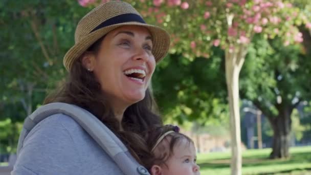 Lycklig kvinna håller sitt barn i en vagn i en park — Stockvideo