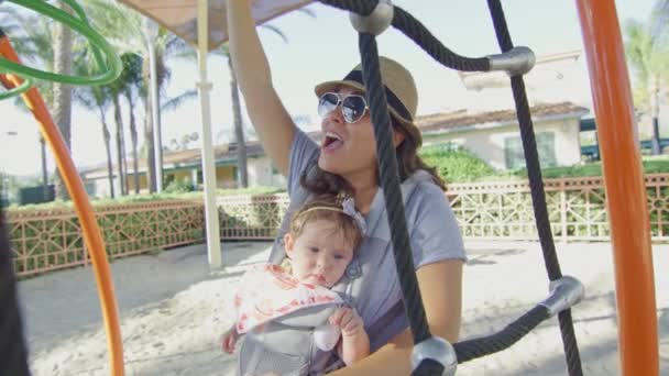 Vrouw genieten van speeltuin met haar baby in een drager — Stockvideo