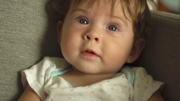 Közelkép a kék szemű babáról, ahogy a kamera felé néz és mosolyog — Stock videók