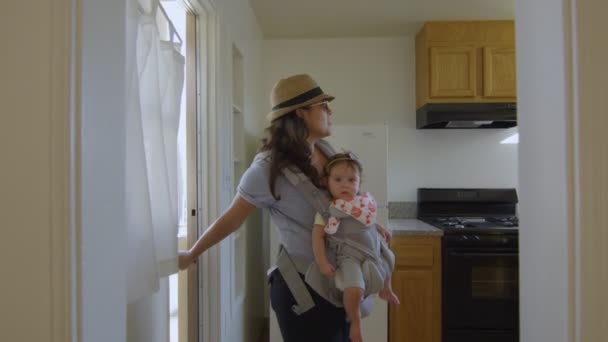 Жінка з дитиною дивиться навколо порожньої квартири — стокове відео