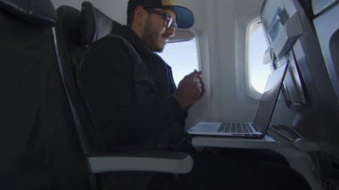 Uçakla seyahat ederken laptoptan almak için kredi kartıyla ödeme yapan adam.