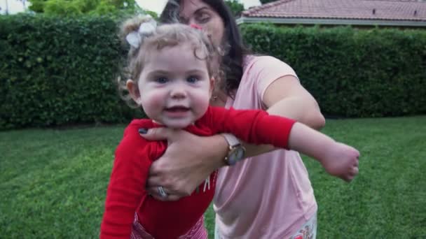 Mujer en patio balanceando a su hija bebé en sus brazos — Vídeos de Stock