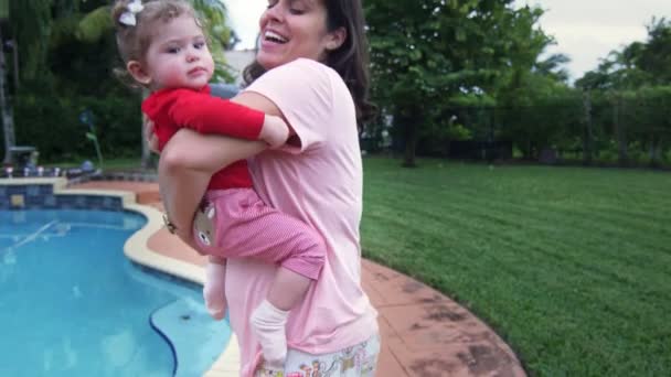 Madre sosteniendo bebé hija en su ams por piscina en casa — Vídeos de Stock