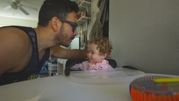 Father kissing baby daughter on forehead during feeding time — Stock Video