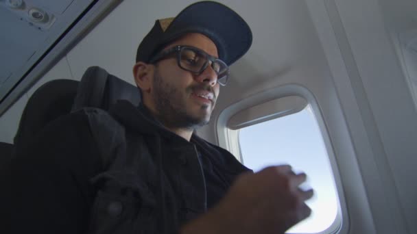 Человек в самолете улыбается, когда читает и печатает на ноутбуке — стоковое видео