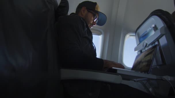 Человек, работающий на ноутбуке во время полета на самолете — стоковое видео