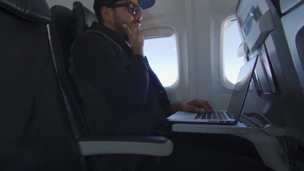 Man på flygplan arbetar på laptop, plötsligt tänker på något stort — Stockvideo