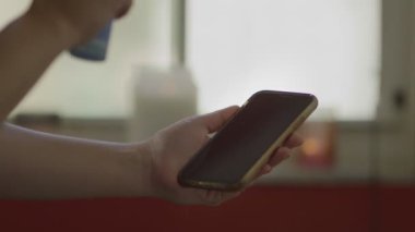 Karantina sırasında cep telefonunu dezenfekte eden ellere yakın çekim