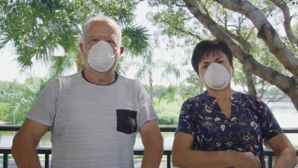Casal de idosos com máscaras faciais olhando para a câmera durante a quarentena — Vídeo de Stock