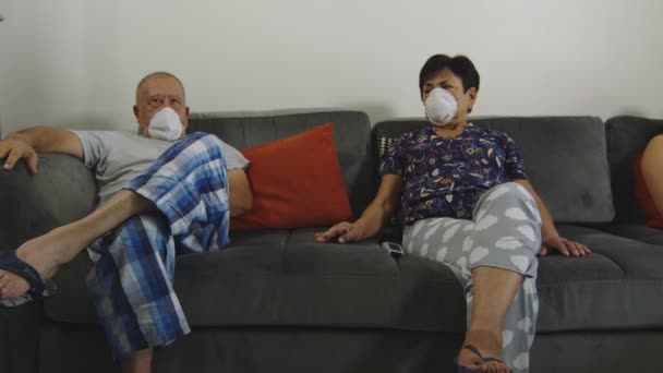 Pareja mayor mirándose con preocupación mientras usa mascarilla en casa — Vídeo de stock