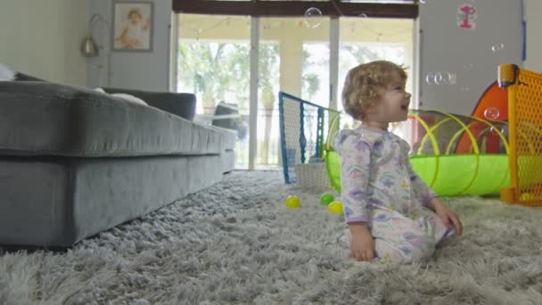 Дитяча дівчинка посміхається на бульбашки вдома — стокове відео