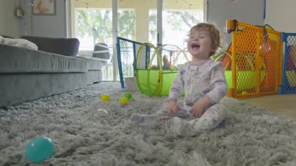 Щаслива дівчинка посміхається і грає з бульбашками вдома — стокове відео