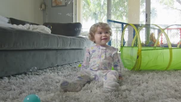 Mouvement lent de bébé fille jouant avec des bulles à la maison — Video