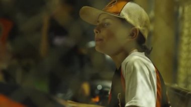 Beyzbol maçı sırasında yedek kulübesinde oturan genç çocuğun orta boy fotoğrafı.