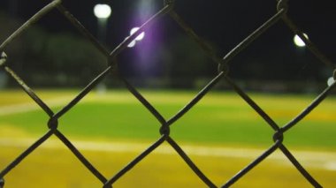 Arka planda bulanık beyzbol sahası olan çitin yakın çekimi