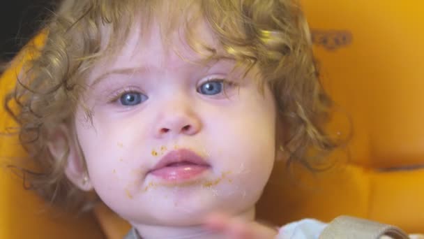 Baby meisje kijken naar camera met vuile mond na het eten — Stockvideo