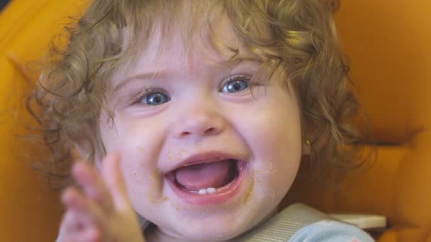 La bambina applaude e sorride alla macchina fotografica con la bocca sporca dopo aver mangiato — Video Stock