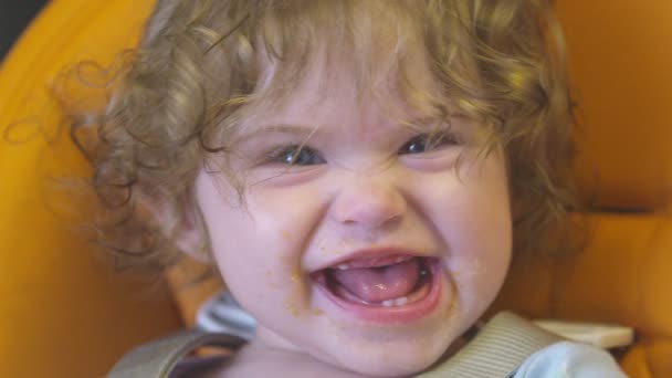 Baby meisje maken grappig gezicht naar camera met vuile mond na het eten — Stockvideo