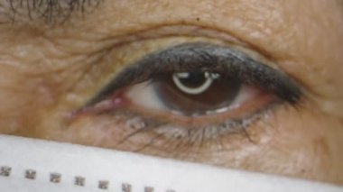 Macro, yaşlı kadınların maske takarken gözlerini yakın plan çek.