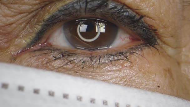 Macro close-up pan de olhos de mulheres idosas enquanto usava uma máscara — Vídeo de Stock