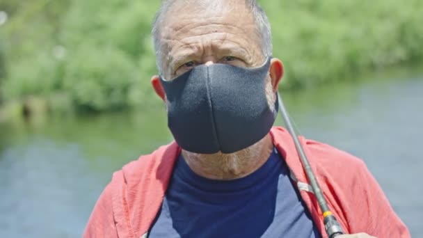Hombre mayor mirando hacia la cámara con máscara protectora en — Vídeo de stock