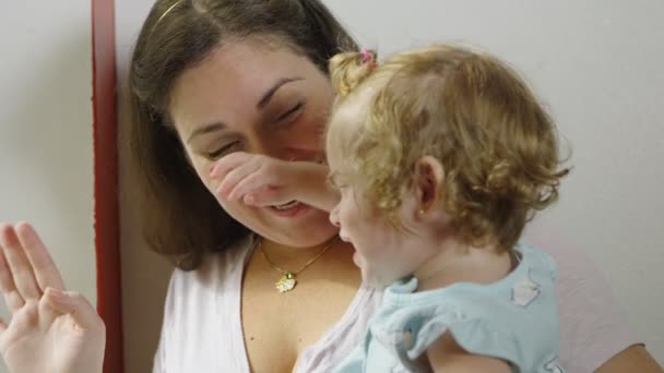 Mother and daughter waving through a window and smiling at home — Stock Video